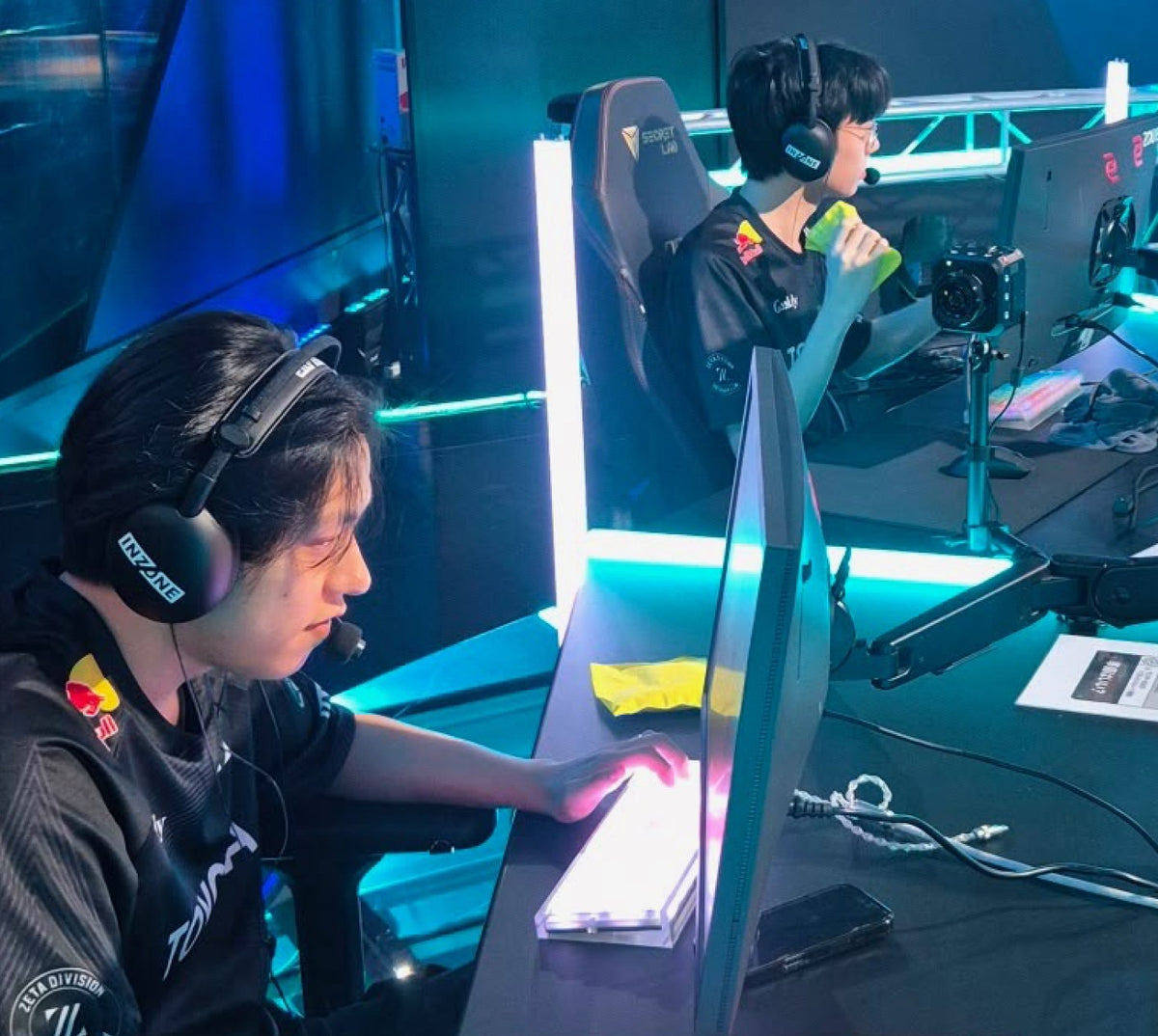 Players on stage at VCT Pacific with a yellow PREF*RE pouch on the desk