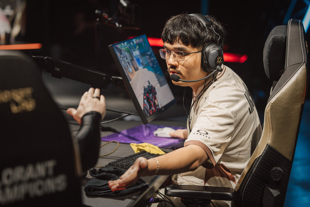 G2 player on stage reaching across a desk with a yellow pouch on it